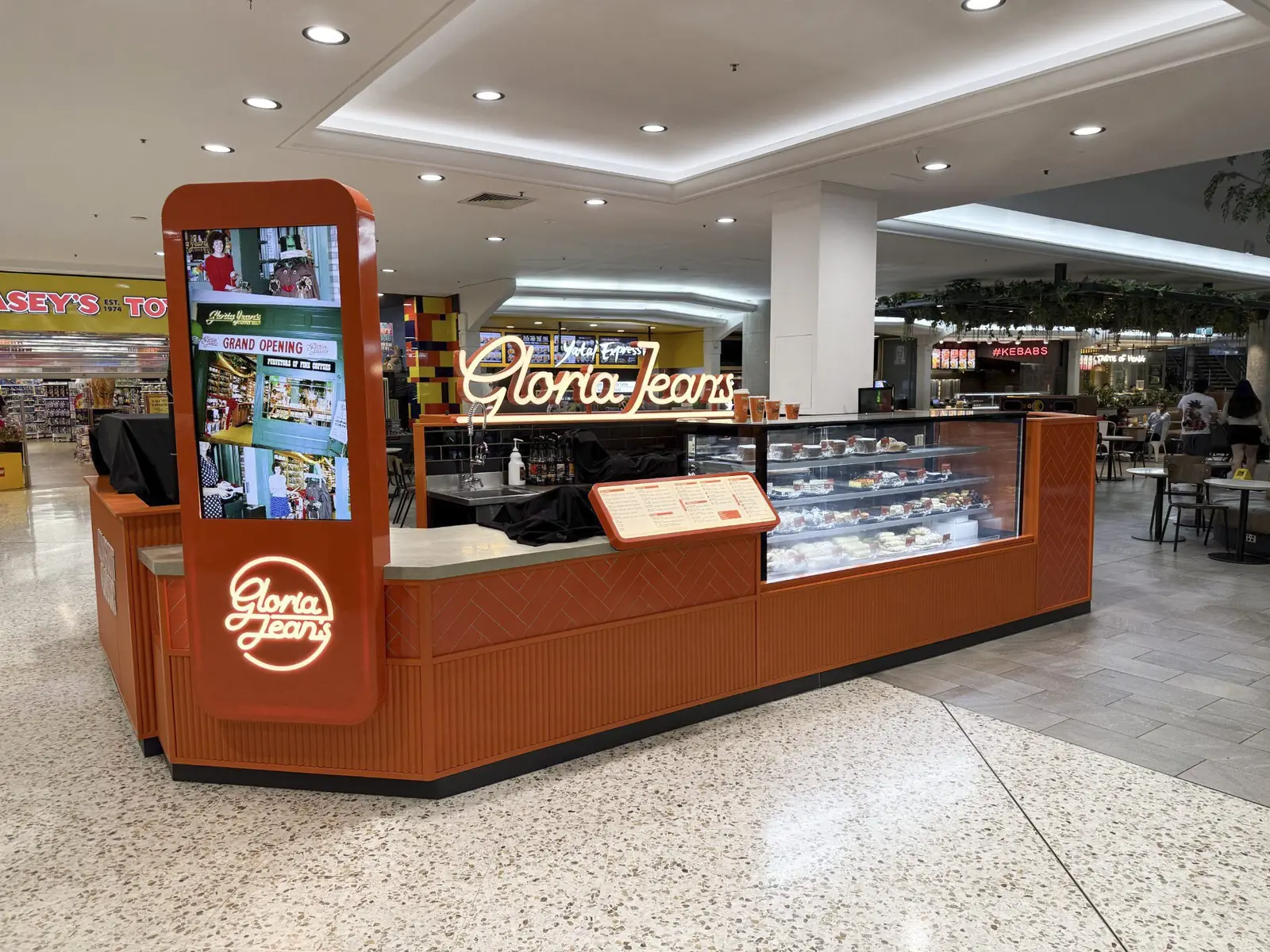 Gloria Jean's Mt Druitt food court kiosk with orange herringbone tile cladding and illuminated signage